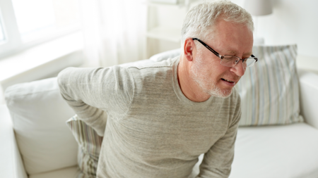 Man holds his back in pain