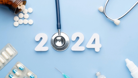 A stethoscope forms the zero in ‘2024’ on a light blue background, surrounded by various medical items such as pills, a syringe and a stethoscope.
