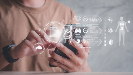 Una persona in camicia marrone utilizza uno smartphone. Simboli medici olografici sono visualizzati insieme a grafici e dati.