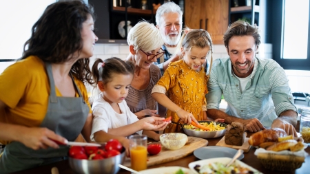 Eine Familie versammelt sich um eine Küchentheke und bereitet Essen zu.