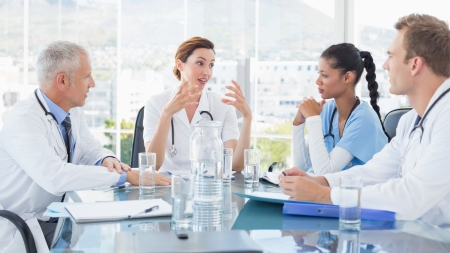 Medizinische Fachpersonen diskutieren an einem Glastisch