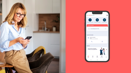 A woman wearing glasses sits in a modern kitchen looking at her phone. Next to her, an illustration of a smartphone screen shows a business app with tasks and contact options against a red background.
